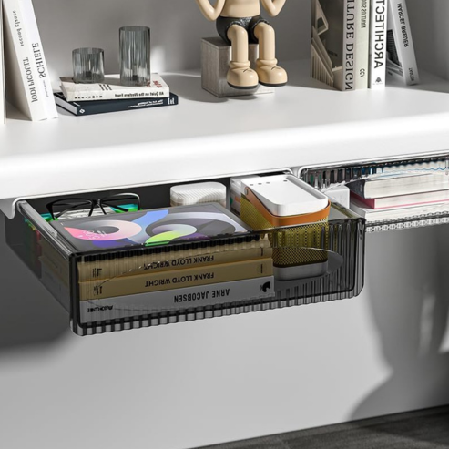A Boîte de rangement à tiroir auto-adhésive sous table – tiroir caché de grande capacité pour bureau tient livres, carnet, lunettes et boîte blanche sous un bureau blanc ; dessus : livres, pot à crayons, figurine articulée beige.